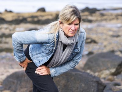 An active mature woman experiencing hip pain during a walk